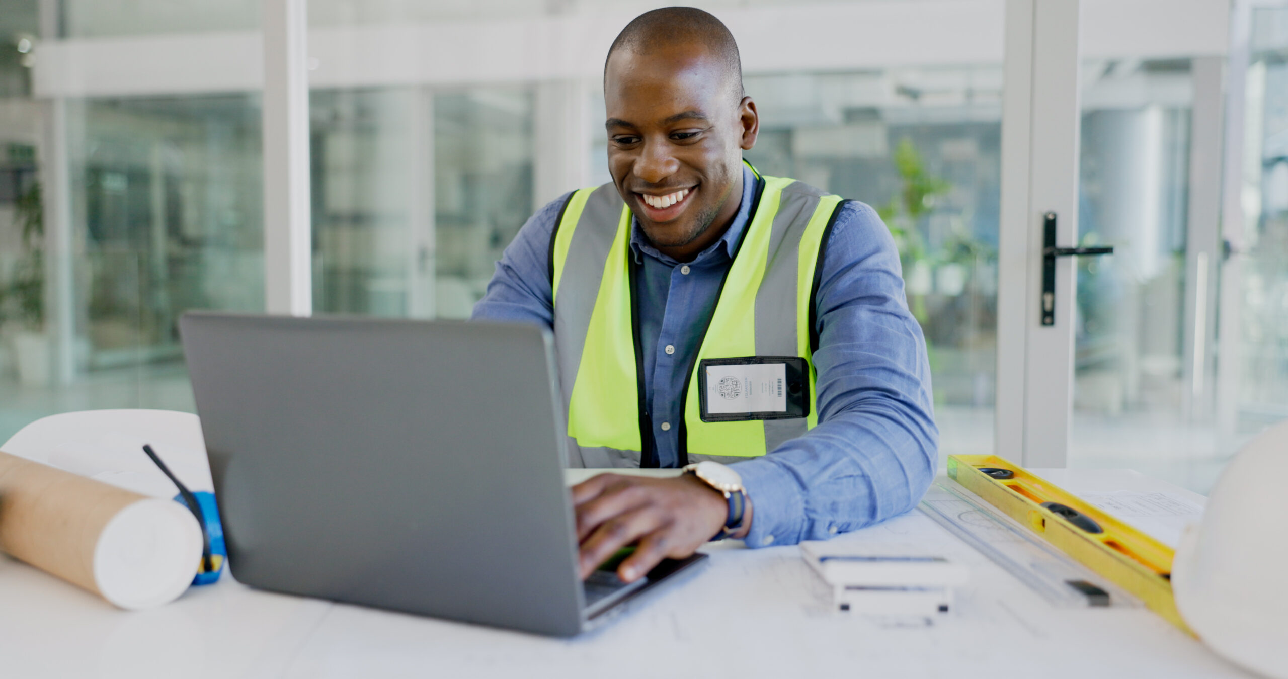 Image of a construction worker works on a construction site on a laptop.