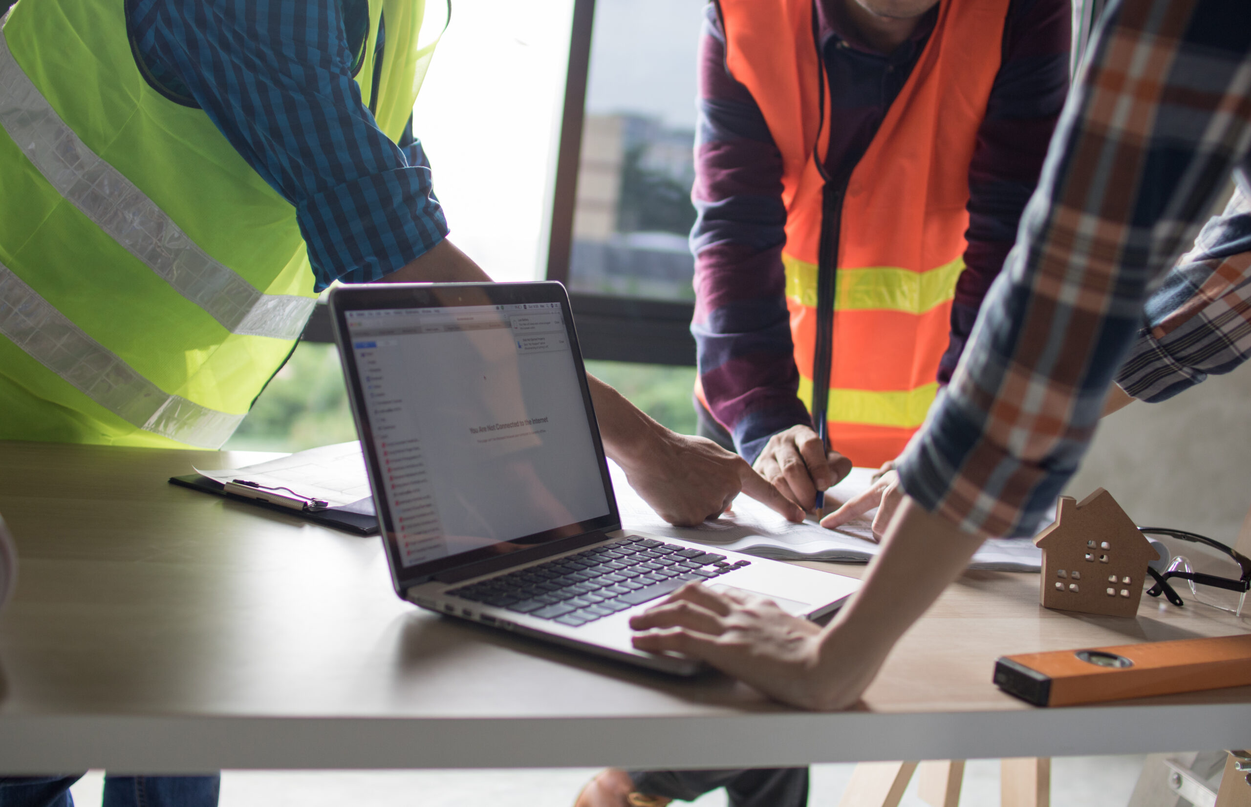 Image of a laptop with various construction equipment around for budget control software