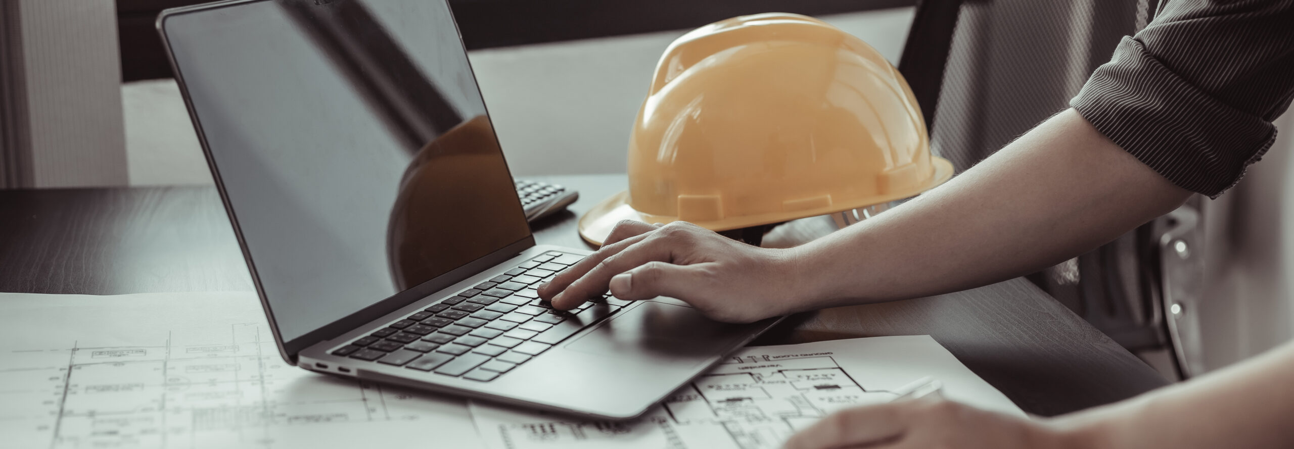Image of a laptop with various construction equipment around for budget control software