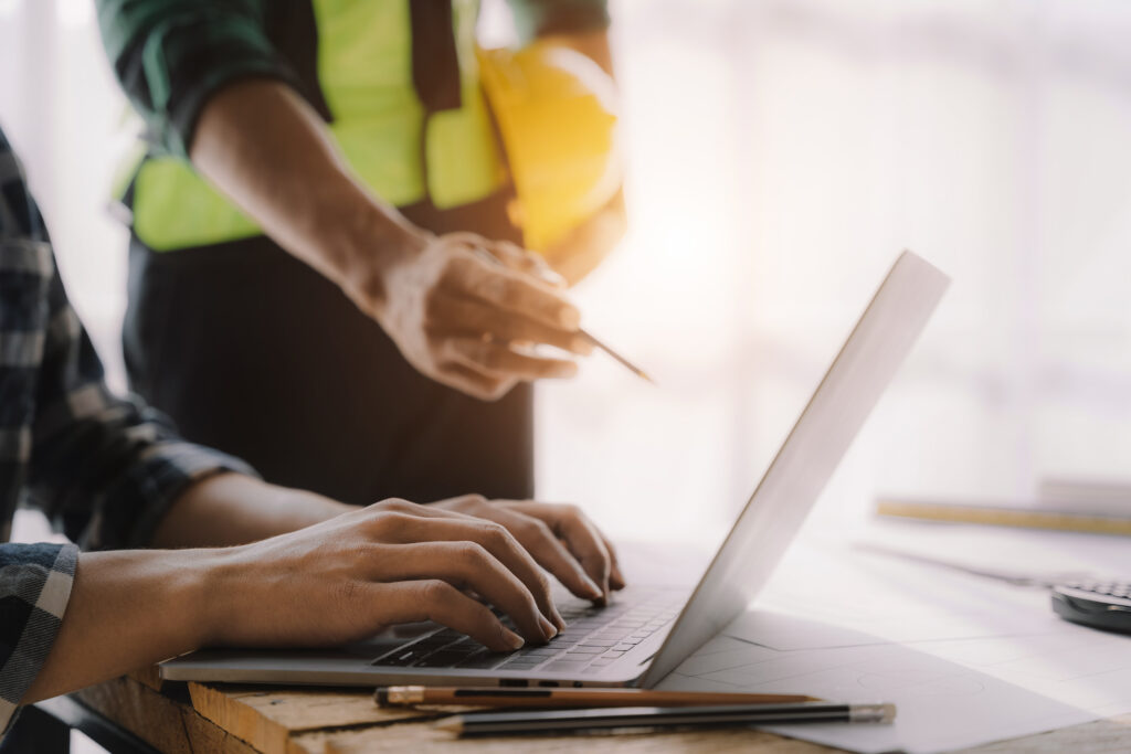 Image of construction workers pointing at a laptop for construction budget manager software