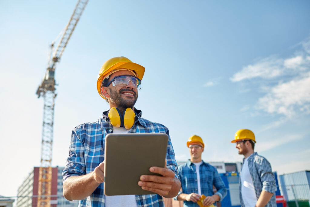 Image of a builder in hardhat with tablet pc at construction